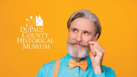 Smiling gray-haired man with a mustache, wearing a blue shirt and orange bow tie, against an orange background.