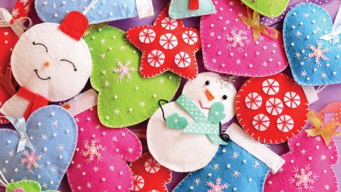 Colorful felt Christmas ornaments, including snowmen, hearts, stars, and trees, decorated with white stitching.