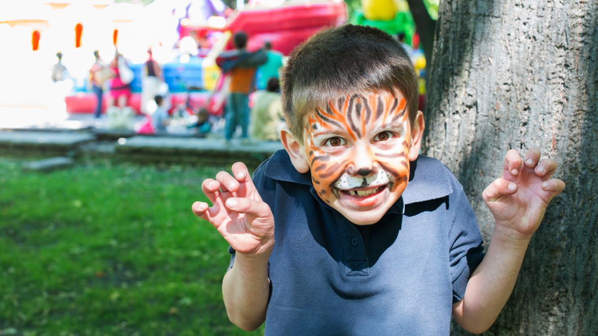 Boy with face paint standing at a carnival