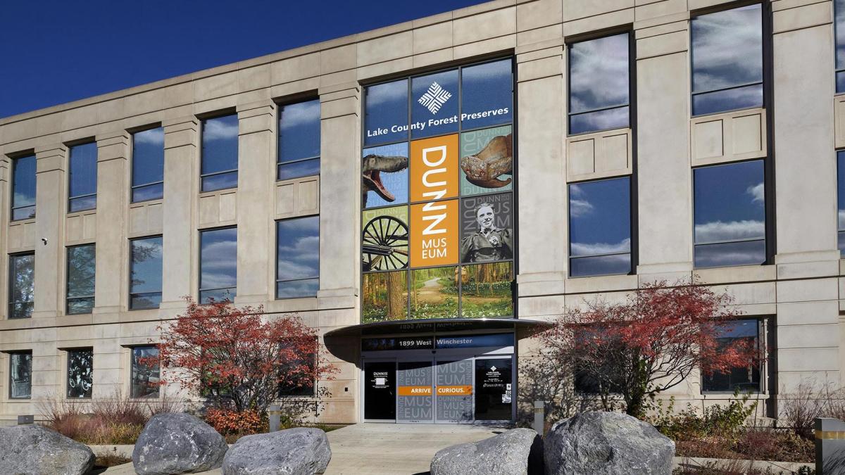 Building with a large banner for Dunn Museum; features nature images and trees in front.